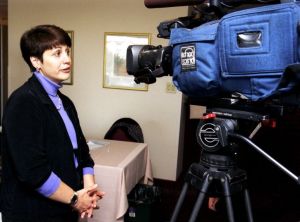 Une femme est intervieweée devant une caméra de télévision.